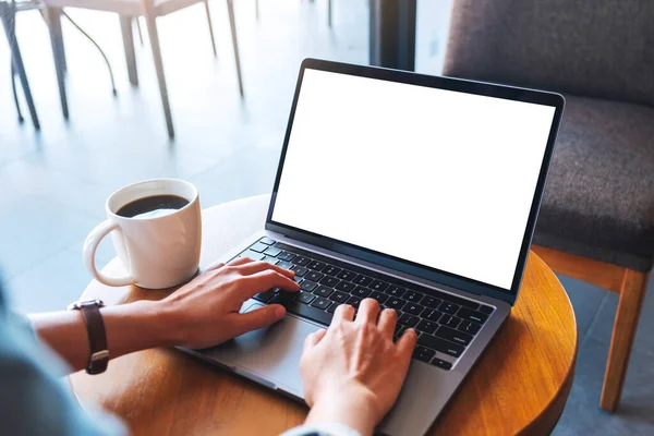 Masada boş beyaz masaüstü ekran ile dizüstü bilgisayarda yazı yazan bir elin görüntüsü