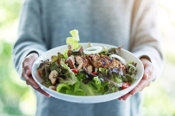 Yakından bakınca elinde bir tabak tavuk salatası tutan bir kadın görülüyor. 