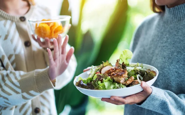 Kadınlar patates cipsi yemeyi ve sebze salatasını reddetmek için el işareti yapmayı seçiyorlar.