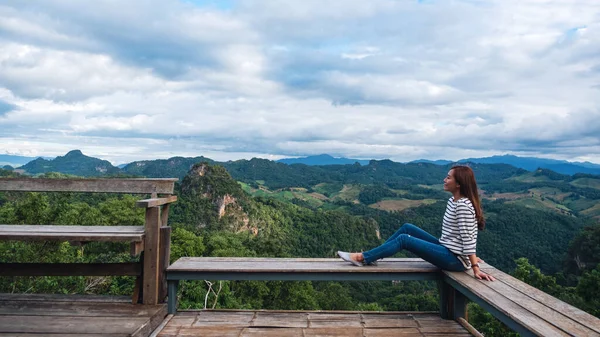 Oturan ve güzel bir dağ manzarasına bakan bir kadın gezginin portresi. 