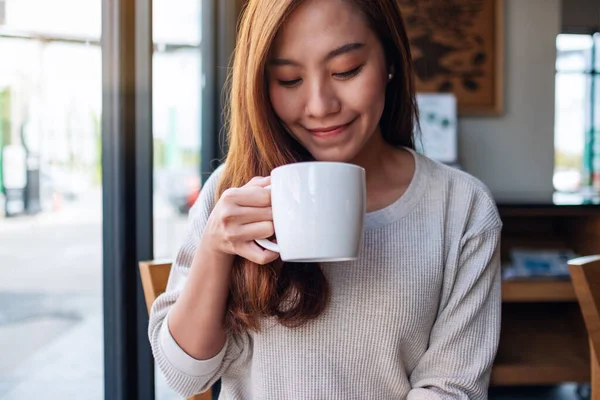 Kafede elinde kahve tutan ve içen Asyalı güzel bir kadının yakın plan görüntüsü.