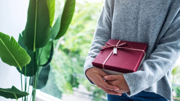 Kırmızı hediye kutusunu elinde tutan bir kadının yakın plan görüntüsü.