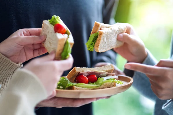 Bir grup genç, tahtadan bir tabakta tüm buğday sandviçini tutuyor ve yiyorlar.