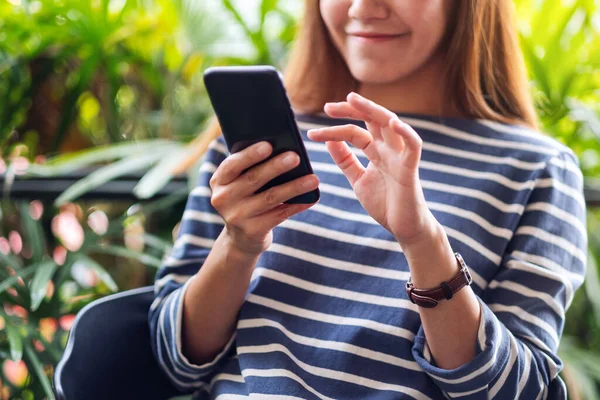 Güzel bir Asyalı kadının cep telefonu tutarken ve kullanırken çekilmiş yakın plan fotoğrafı. 