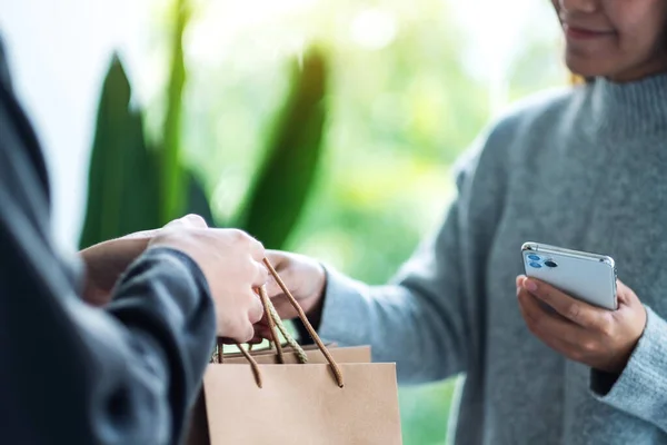 Een Vrouw Die Een Mobiele Telefoon Vasthoudt Boodschappentassen Ontvangt Van — Stockfoto