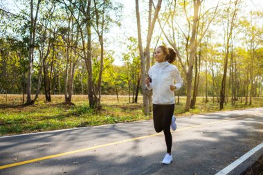 Genç Asyalı bir kadın sabah şehir parkında koşuyor.
