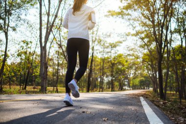 Sabahları şehir parkında koşan Asyalı bir kadının arka plan görüntüsü.