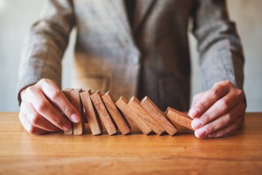 Bir iş adamının yakın plan görüntüsü iş konseptine kanarken tahta bloğu tutmaya çalışır.