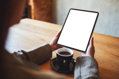 Masasında kahve fincanı olan siyah tabletli beyaz ekranlı bir kadının görüntüsü.