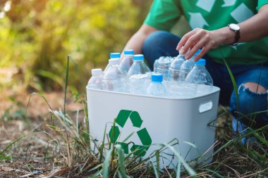 Dışarıdaki çöp kutusuna plastik şişe toplayan bir kadın.