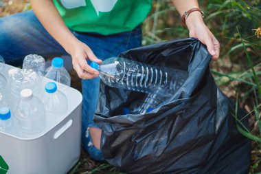 Geri dönüşüm konsepti için plastik şişeleri bir kutuya koyan bir kadın.