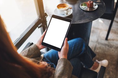 Boş beyaz masaüstü ekran ile siyah tablet bilgisayarını tutan bir kadının en üst görünüm görüntüsü 