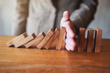 İş adamının yakın plan görüntüsü. İş çözümü kavramı için tahta domino taşlarını durdurmaya çalış. 