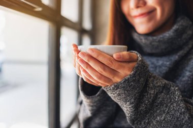 Yakından bakınca Asyalı güzel bir kadının elinde bir fincan sıcak kahve tutarken görüntüsü.