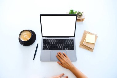 Top view mockup image of hands using and touching on laptop touchpad with blank white desktop screen on the table