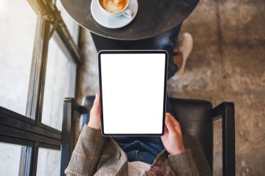 Kafede elinde siyah tablet olan beyaz ekranlı bir kadının üst görünüm görüntüsü