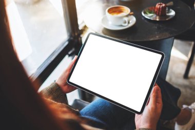 Kafede elinde siyah tablet olan beyaz ekranlı bir kadının görüntüsü.