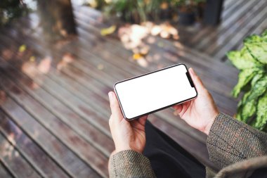 Boş beyaz masaüstü ekran ile siyah bir cep telefonu tutan bir kadının görüntüsü 