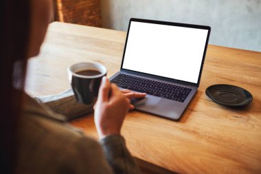 Kahve içerken bilgisayardaki dokunmatik dokunmatik dokunmatik ekranlı boş beyaz masaüstü ekranlı bir kadının görüntüsü.