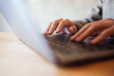 Masada dizüstü bilgisayarda çalışan ve daktilo kullanan bir kadının yakın plan resmi