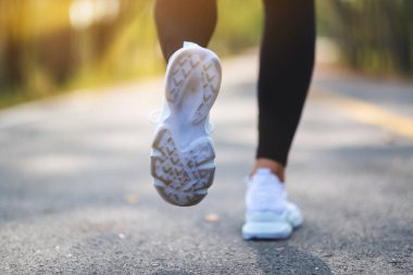 Closeup image of a woman's legs while jogging in city park in the morning