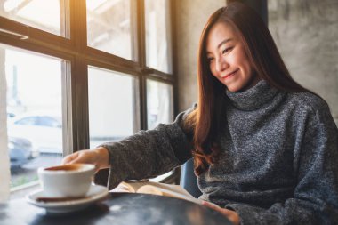 Sabahları kahve içerken kitap okuyan güzel bir kadının yakın plan görüntüsü.