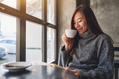 Sabahları kahve içerken kitap okuyan güzel bir kadının yakın plan görüntüsü.