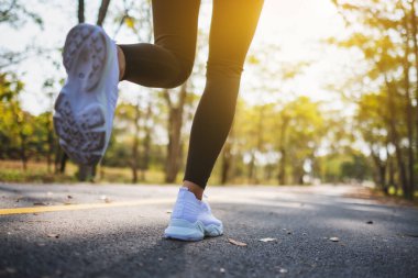 Closeup image of a woman's legs while jogging in city park in the morning