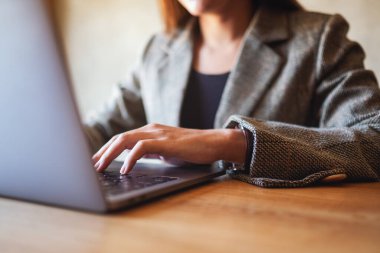 Masadaki dizüstü bilgisayarda çalışan ve daktilo kullanan bir iş kadınının yakın plan resmi.