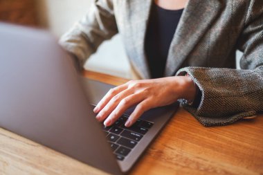 Masadaki dizüstü bilgisayarda çalışan ve daktilo kullanan bir iş kadınının yakın plan resmi.