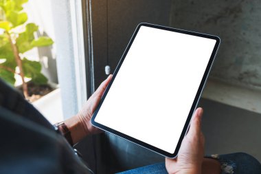 Kafede elinde siyah tablet olan beyaz ekranlı bir kadının görüntüsü.