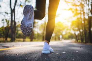 Closeup image of a woman's legs while jogging in city park in the morning
