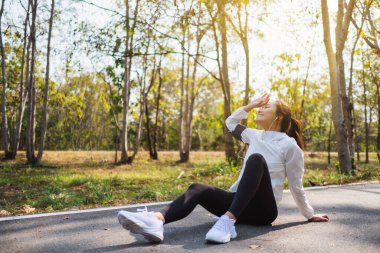 Şehir parkında sokakta oturan Asyalı bir kadın koşucunun yakın çekimi.