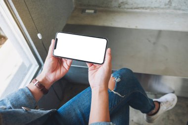 Siyah cep telefonunu boş ekran ile tutan bir kadının görüntüsü. 