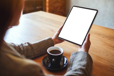 Masasında kahve fincanı olan siyah tabletli beyaz ekranlı bir kadının görüntüsü.