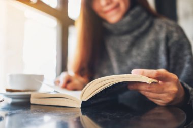 Yakından bakınca, elinde kahve fincanı olan ve kitap okuyan güzel bir kadın görülüyor.