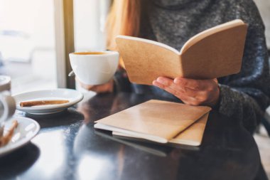 Sabahları kahve içerken kitap okuyan güzel bir kadının yakın plan görüntüsü.