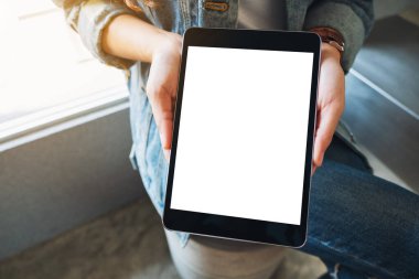 Kafedeki boş beyaz ekranlı siyah tableti tutan ve gösteren bir kadının görüntüsü