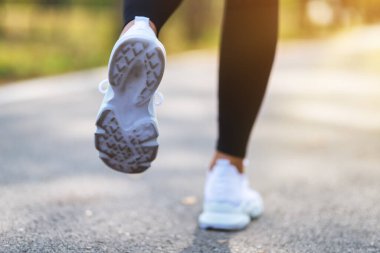 Sabah şehir parkında koşarken bir kadının bacaklarının yakın görüntüsü.