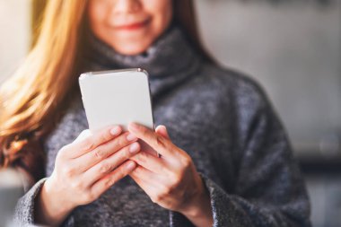 Güzel bir kadının cep telefonu tutarken ve kullanırken yakın plan görüntüsü. 