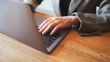 Masada dizüstü bilgisayarda çalışan ve daktilo kullanan bir kadının yakın plan resmi