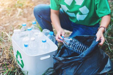 Geri dönüşüm konsepti için plastik poşet ve kutuya çöp şişesi koyan bir kadın.