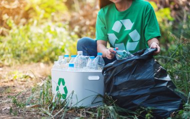 Geri dönüşüm konsepti için plastik poşet ve kutuya çöp şişesi koyan bir kadın.