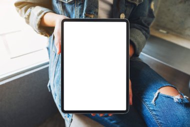 Kafedeki boş beyaz ekranlı siyah tableti tutan ve gösteren bir kadının görüntüsü