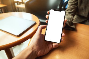 Boş siyah masaüstü ekranı olan beyaz cep telefonunu tutan ve gösteren bir kadının görüntüsü