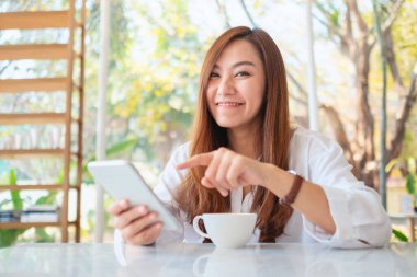 Güzel bir Asyalı kadının cep telefonunu kullanırken ve işaret ederken yakın plan görüntüsü.