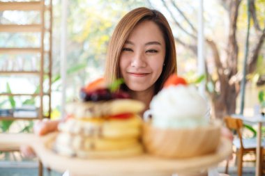 Güzel bir Asyalı kadın elinde bir tabak krep, dondurma ve kafede krema tutuyor.