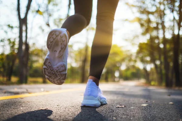 Sabah şehir parkında koşarken bir kadının bacaklarının yakın görüntüsü.