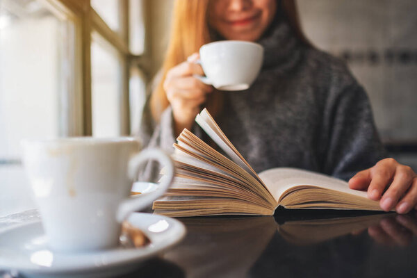 Крупный план, изображающий красивую женщину, читающую книгу во время утреннего кофе