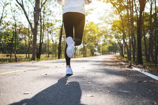 Sabahları şehir parkında koşan Asyalı bir kadının arka plan görüntüsü.